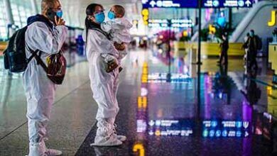 Image: Travellers in protective suits are seen at Wuhan Tianhe International Airport in Wuhan